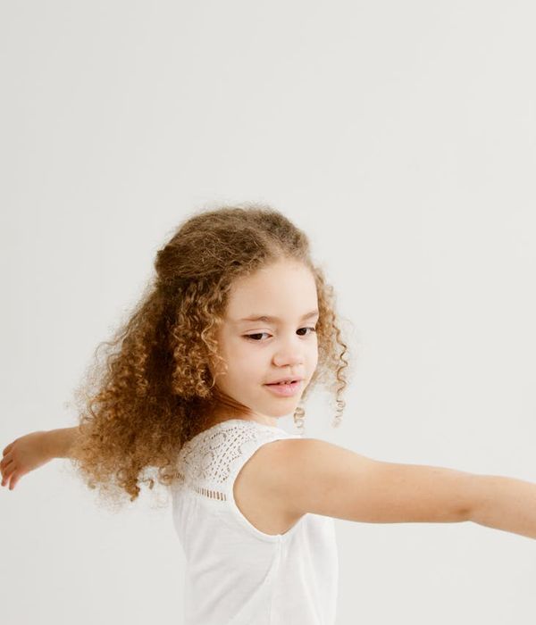 Joyful child in a playful yoga pose, smiling brightly.